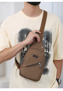 Brown canvas crossbody bag with adjustable strap and leather logo detail shown on model