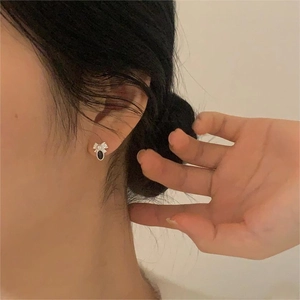 Detailed view of elegant black bow pearl stud earring worn on model's ear