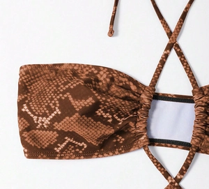 Detailed macro view of snakeskin print swimwear fabric with halter tie and pleated texture