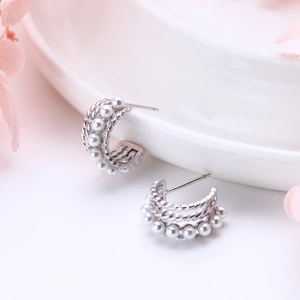S925 sterling silver C-shaped twisted earrings with pearls on a white porcelain plate