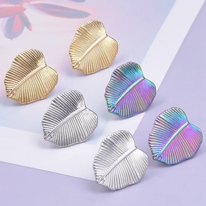 Dettaglio macro di orecchini a foglia in acciaio inossidabile oro, argento e arcobaleno
