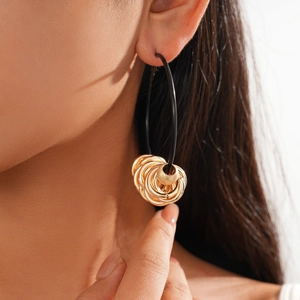 Close-up of model wearing black leather cord hoop earrings with gold metal rings