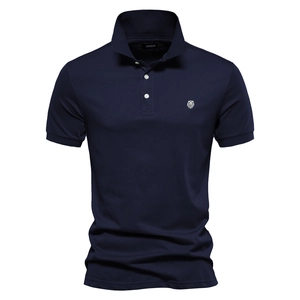 Détail du polo en coton piqué bleu marine avec broderie tête de lion blanche sur la poitrine