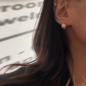 Detail of single pearl stud earring with golden base on model showing elegant ear styling