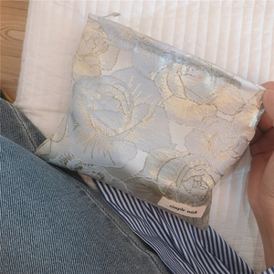 Detail of elegant gold jacquard rose pattern on blue brocade cosmetic pouch fabric