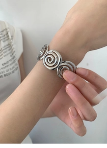 Detailed view of silver spiral metal bracelet with polished geometric texture on wrist