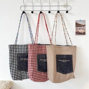 Three plaid tote bags with denim pockets and colorful braided straps hanging on a wall