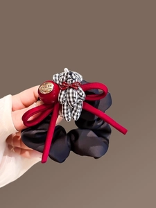 Detail of plush bear and velvet bow scrunchie held by hand showing quality