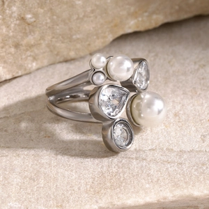 Detail of 18k gold plated ring with irregular white zircon and faux pearls on stone background