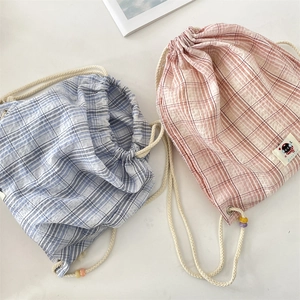 Detail of checkered drawstring backpacks with beaded cords and seersucker fabric texture