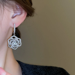 Close-up detail of silver rose earrings with pavé-set zircons worn by a model