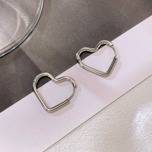 Close-up of heart-shaped silver stainless steel hoop earrings on a two-tone background