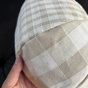 Macro view of beige plaid linen newsboy cap showing fine fabric texture and stitching