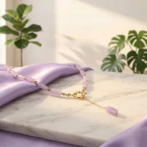 Detailed shot of amethyst bead necklace with gold clasp on white marble surface