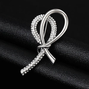 Detailed view of a silver knotted ribbon brooch with sparkling crystals on black leather