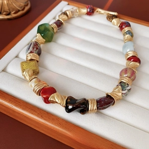 Vintage floral ceramic beaded necklace with gold accents on a white jewelry tray