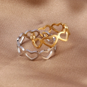 Retro minimalist gold and silver heart cutout rings displayed on brown satin