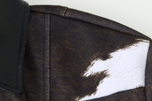 Close-up of cow print jacket featuring faux fur texture and black leather collar detail