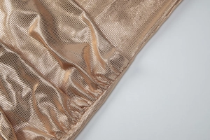 Détail du tissu métallique doré montrant une texture de maille fine et des drapés polis