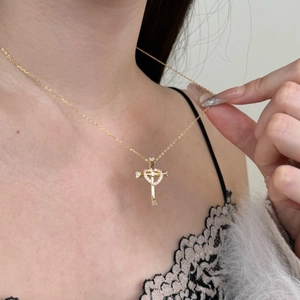 Detail of a gold cross and heart pendant necklace with shimmering crystals on a model