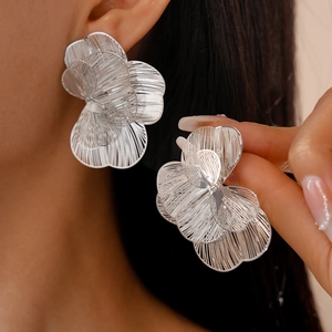 Detail of silver hollow flower stud earrings showing the layered metallic petal design