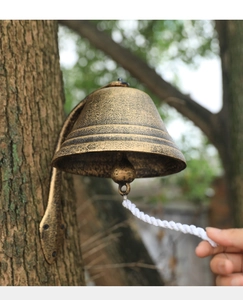 Detail of vintage bronze cast iron doorbell with woven rope mounted on a tree trunk