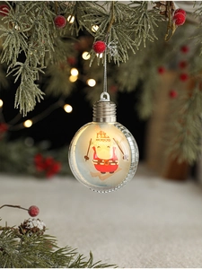 Close-up of clear Christmas ornament with a skiing figure hanging on a festive pine tree