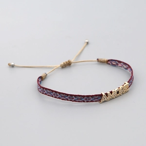 Macro detail of hand-woven geometric bracelet featuring rhinestone AMORE letter charm