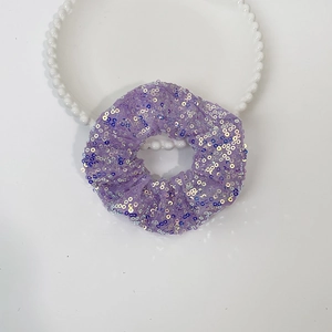 Close-up of a purple sequined LED scrunchie with sparkling details on a clean surface
