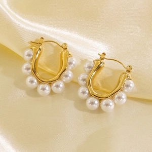 U-shaped gold titanium steel earrings with white pearls on champagne silk fabric
