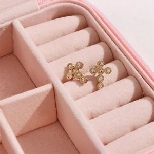 Macro shot of gold cross stud earrings with sparkling diamonds in a pink velvet box
