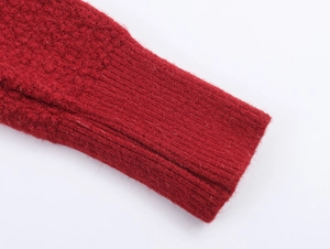 Vista macro di un cardigan rosso in maglia con spessi polsini a coste e trama morbida