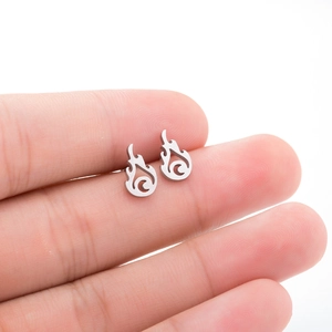 Macro shot of silver flame-shaped stainless steel stud earrings held between fingers