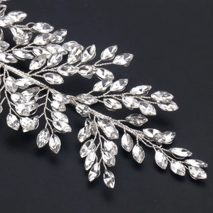 Detail of handcrafted bridal headband with crystal leaves and woven metal wire on black background