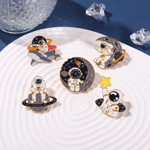 Set of 5 astronaut enamel pins with whale and star designs on a white wave plate