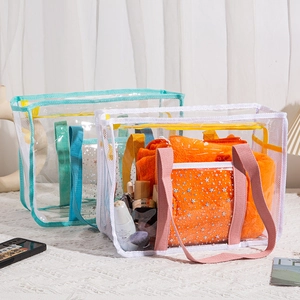Detail of transparent PVC beach bags with pink and blue handles and silver star patterns