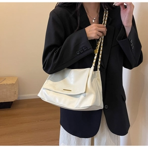 Close-up of a white synthetic leather shoulder bag with a gold chain strap and metal buckle