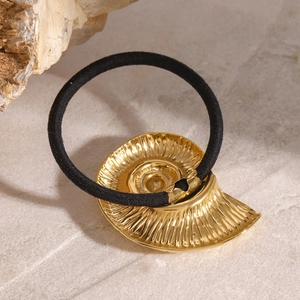 Elastic black hair tie with gold conch shell charm on natural stone surface