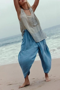Detailed texture of blue striped straight-leg pleated trousers on a sunny beach background