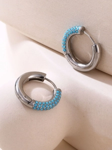 Macro shot of silver titanium steel hoop earrings with turquoise blue stone beads