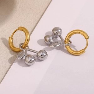 Vue macro des boucles d'oreilles cerises bicolores avec anneau doré et pendentif argent