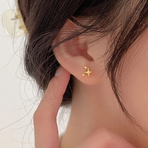 Close-up of golden triple star stud earrings worn on model for a minimalist aesthetic