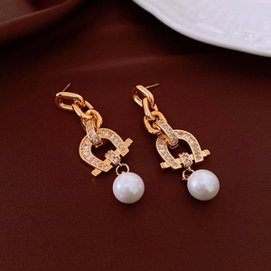 Detail of long gold drop earrings with pave zircon horseshoe links and hanging white pearl
