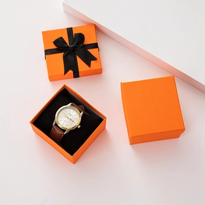 Detail of quartz watch with brown leather strap in an orange gift box with black ribbon