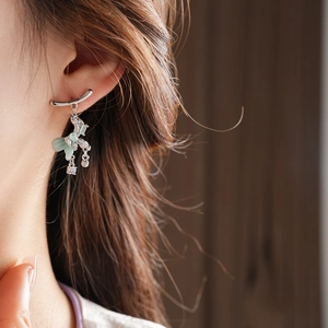 Detailed view of silver bow earrings with light green zircon tassels on a model