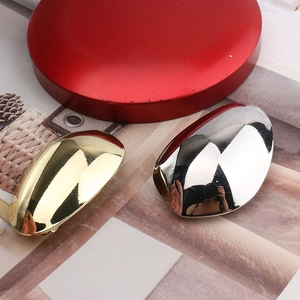 Detail of mirror-polished gold and silver egg-shaped metal hair clips with high reflection