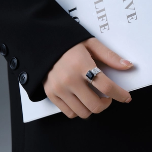 Detail of silver watch-strap ring with black square gemstone worn by model