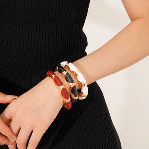 Detailed close-up of fashion enamel gold bangles in red, black and white colors