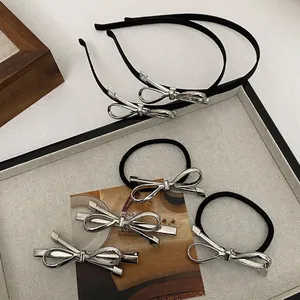 Silver bow hair accessory set including headbands, hair ties and clips on white tray