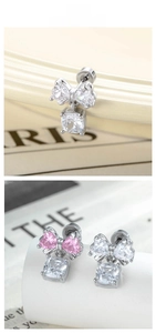 Detailed view of bow-shaped cartilage earrings with dangling square-cut zircons